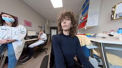 A fish eye lens still from the film Convulsive States, featuring the artist Liz Magic Laser and two doctors in the background, to advertise the screening and discussion event.