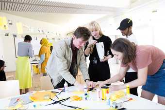 Whitechapel workshop, young people leaning over table