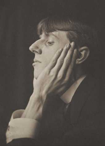 black and white photo of a young man with his face in his hands