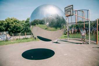 photograph of of the artist Allard and a large silver ball mid bounce in a basketball court