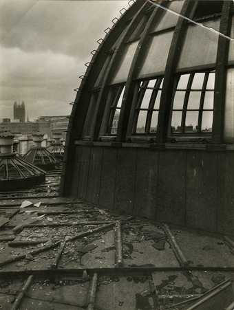 Black and white photo of the bomb damage to the Rotunda roof dome.  Their is shattered glass and debris visible.