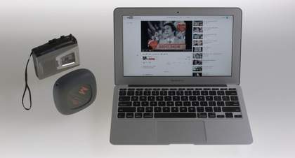 A laptop is open with a youtube video playing on it with two gadgets beside it 