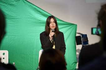 woman holding a microphone in front of a green screen