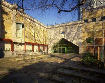 The Clore Gallery entrance, there is a clear blue sky and branches and shadows across the image.