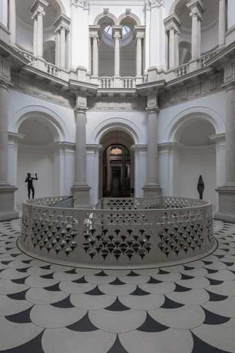 Front view of Tate Britain rotunda, the gallery is made of white stone with alcoves and pillars.  There are statues in the alcoves and a balustrade.