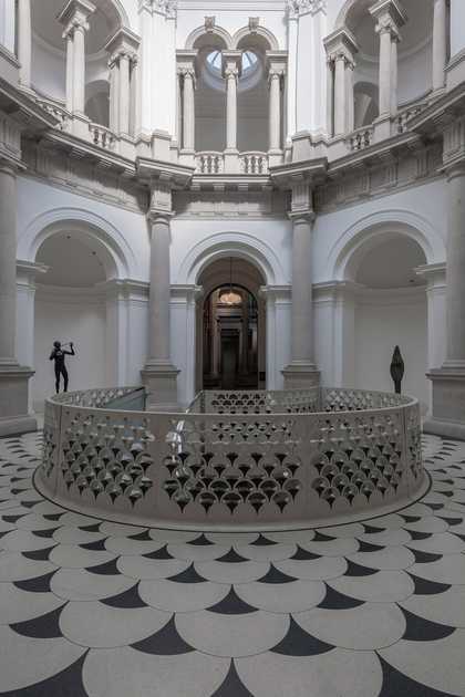 Front view of Tate Britain rotunda, the gallery is made of white stone with alcoves and pillars. There are statues in the alcoves and a balustrade.