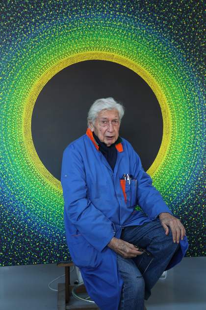 Julio Le Parc, in front of one of his works forming a circle halo around his head