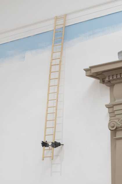 Jesse Darling's installation, two hands coming out of a white wall holding a ladder