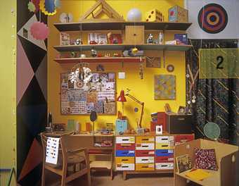 Chapters One to Five, 2012, Production Still of colourful studio with shelves, desk, chair and hanging mobiles