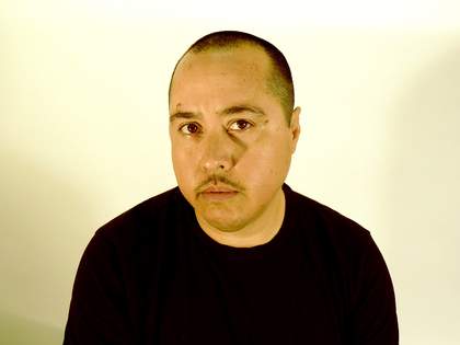 Portrait of Chris E. Vargas in front of a white background, wearing a black shirt.