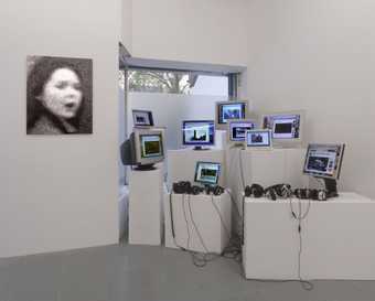 Installation view of monitors showing remakes of John Smith's The Girl Chewing Gum 1976 in the exhibition unusual Red cardigan