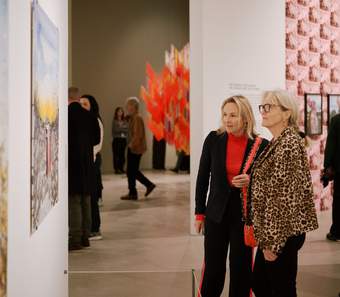 Two visitors discussing artworks in the Outi Pieski exhibition