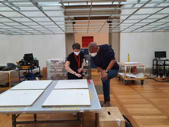 Two people study objects on a table