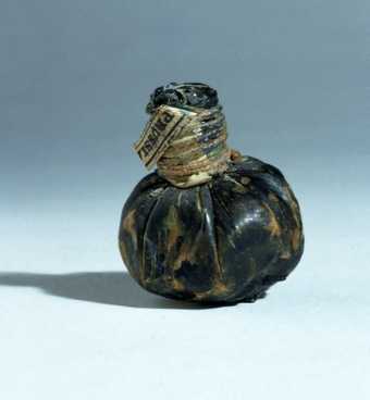 Pig's bladder pouch, looks like a dark brown round nut, gathered at the top and enclosed with a cord or string wrapped around
