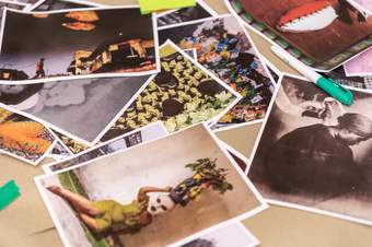A pile of printed, colourful photographs scattered across a table, ready to be used in a collaging activity