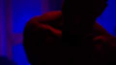 The shadowy head and shoulders of a figure with subtle red and blue lighting in a dimly lit environment