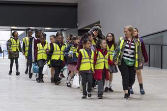A group of students come down the ramp in the Turbine Hall with their teachers