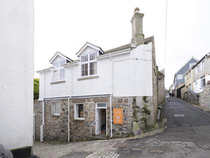 The exterior of the museum from the perspective of the road. The museum is a large, low building with stone and white painted walls. The door is open and there is an orange sign beside it.