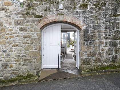 Large, open, white double doors with a curved frame, set into a grey stone wall. There is a metal ramp and banister leading into the building. Through the doors there is a second ramp leading to the garden.