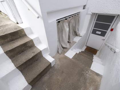 Two small sets of staircases in an L shape, leading down to the ground floor. The steps are made of stone, with metal banisters. There is a closed door with a handle at the base of the steps.