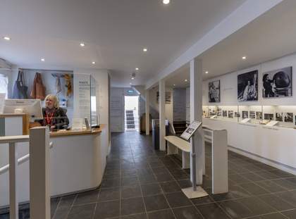 The room is small and bright. To the left, there is a large white counter where a Visitor Assistant sits. To the right there is a long display case.