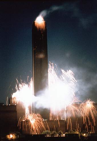 Fireworks and pyrotechnic displays cascade down the exterior walls of a disused power station.