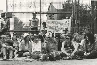 A group of women sat on the ground holding a banner