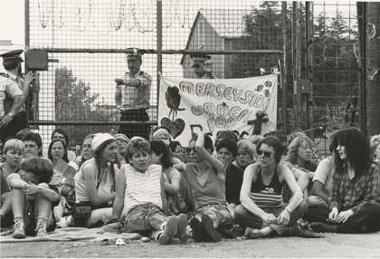 A group of women sat on the ground holding a banner
