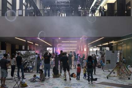 A crowd look on while smoke rings fill the air in Tate Modern's Turbine Hall