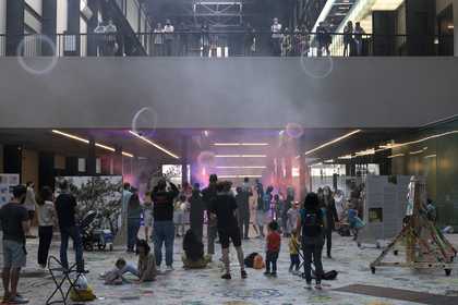 A crowd look on while smoke rings fill the air in Tate Modern's Turbine Hall