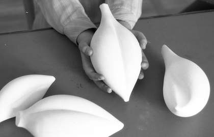 A black-and-white photo of sculpture in the shape of a leaf held in a child's hands