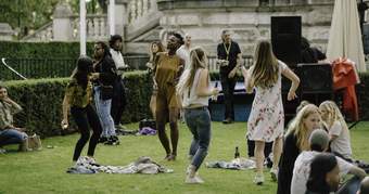 A group of people dancing on the grass outside Tate Britain