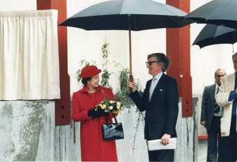 Her majesty the Queen holding a bouquet of flowers accompanied by Tate Director Alan Bowness at the opening of the Clore Gallery in 1982.