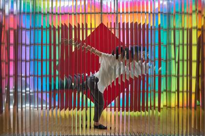 A screen of reflective strips shows a reflection or distorted image of a woman standing on one leg