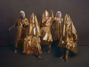 Five performers from Drag Syndrome dressed in gold lame fabric costumes pose for the camera