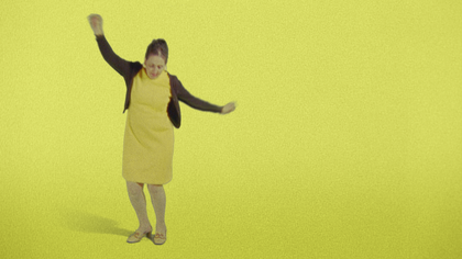 A person in a yellow dress dances in a yellow room