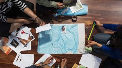 A group of four people undertaking a collage activity on the floor at Tate Britain.
