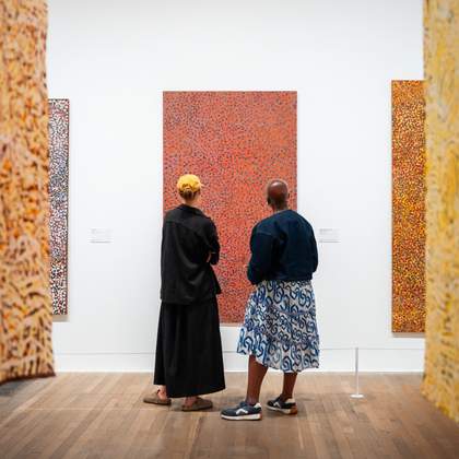 Two people standing in front of an artwork by Emily Kam Kngwarray