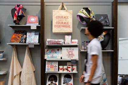 Man with a bag walking in front of a display in a shop.