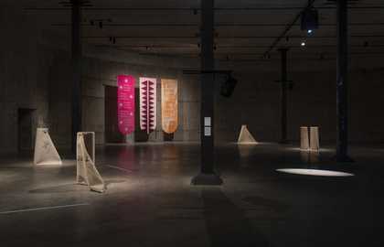 three banners hang on a wall in the tanks with rolled up rugs on the floor