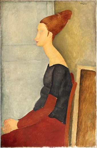 Portrait of Hébuterne, sitting in profile, facing left. Style and pose are similar to fig.4 (slouched shoulders, cone-shaped piled up hair, pale grey wall and canvas shape behind the chair) but the clothing is the dark black and red.