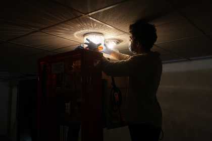 An individual with gloved hands attaching a glass lamp to the ceiling