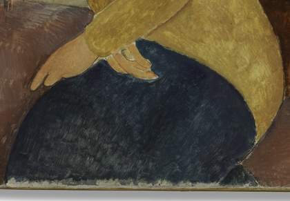 Detail showing the hands crossed in her lap and a dark blue skirt, with the edge of canvas