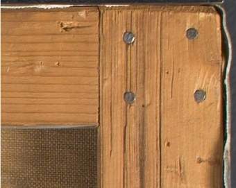 Image of the corner of the wooden strainer, showing the heads of 4 nails.