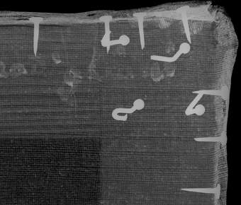 Image of the corner of the wooden strainer. The 4 nails show up white in this x-radiograph image, along with tacks around the outside