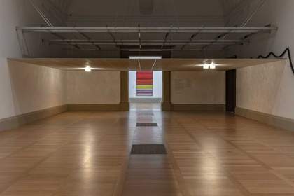 A room in an art gallery with a low ceiling made of tiles, with lamps attached that emit warm lighting