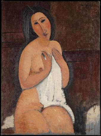 Seated female nude holding up a white shirt with both hands to partially cover her chest, torso and upper thigh. She looks towards the viewer, head tilted to the left.