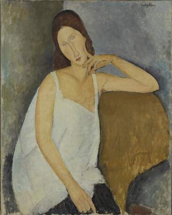 Three-quarter portrait of Hébuterne. She sits in a dark yellow armchair, one arm propped on the top of the chair, a finger of one hand against her cheek, her head tilted to one side, in a playful or flirtatious gesture. She wears a white sleeveless dress.
