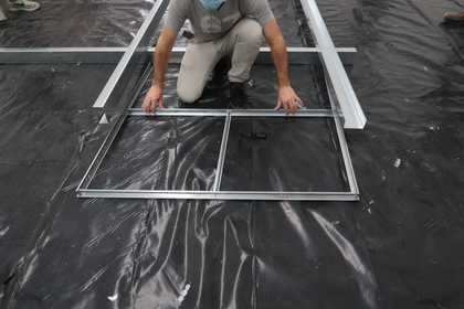 An individual sliding a section of a metal grid into a larger metal structure
