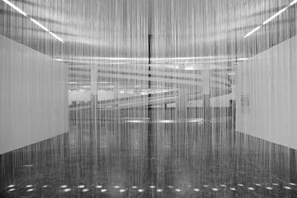 Black-and-white installation photograph showing the many thin nylon threads running vertically across the exhibition space, creating a kind of ethereal veil